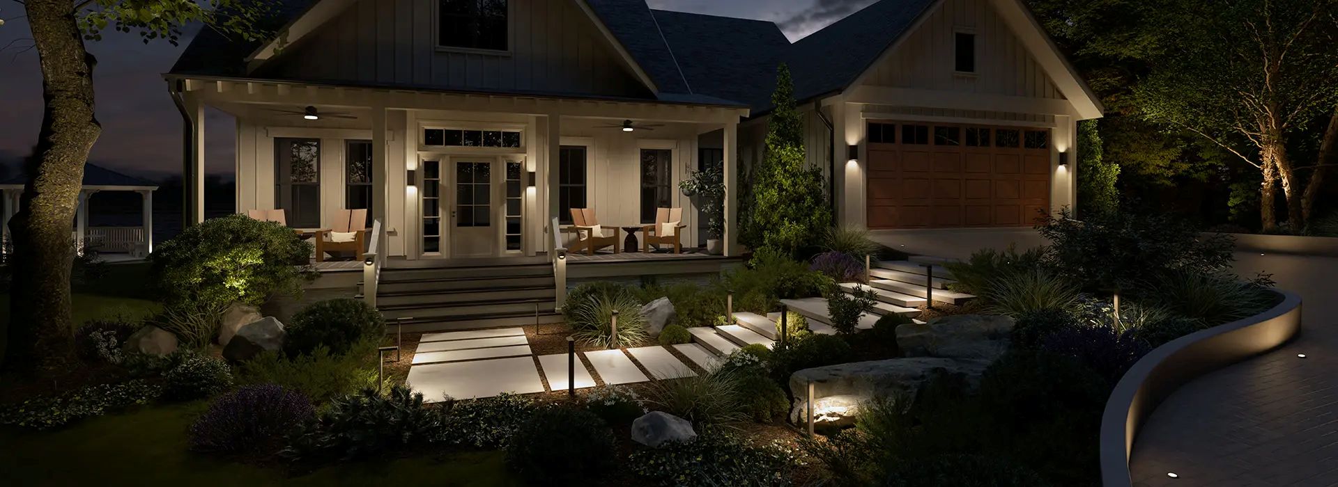 Home at dusk with Kichler landscape lighting illuminating the walkway, planting beds, trees and retaining wall.