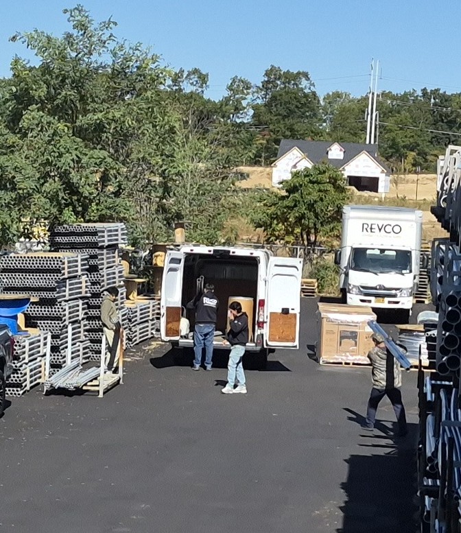 Electrical supply materials, a contractor van, and a Revco delivery truck during material pickup and delivery operations.